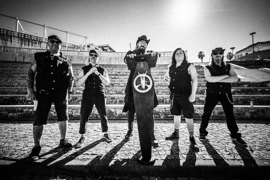 The five members of Unredeemer on cobblestones, the vocalist behind the coffin lectern with the Emblem